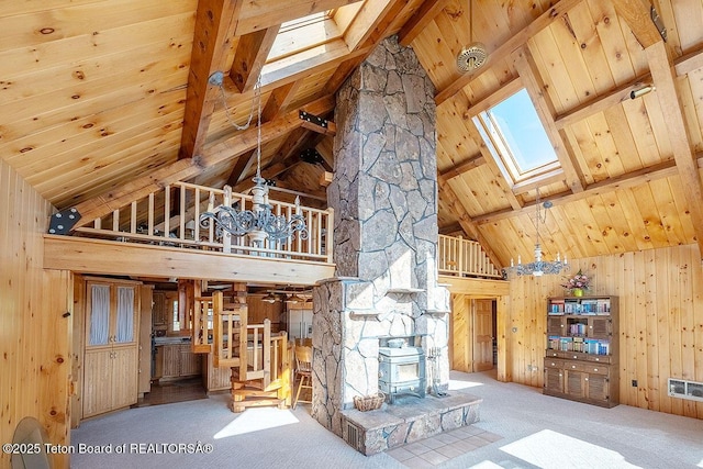 386 Dogwood Dr, Star Valley Ranch, WY 83127 - unfurnished living room featuring a skylight, high vaulted ceiling, carpet flooring, wood walls, and a wooden ceiling with exposed beams