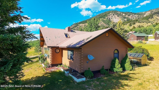 386 Dogwood Dr, Star Valley Ranch, WY 83127 - view of home's exterior with a greenhouse, log exterior, a yard, a mountain view, and an outdoor structure