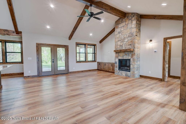245 Pond Dr, Victor, ID 83455 - unfurnished living room with beamed ceiling, french doors, a fireplace, plenty of natural light, and light wood-type flooring
