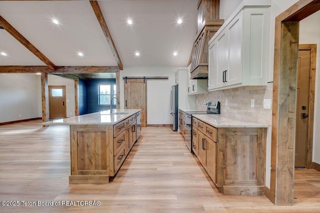 245 Pond Dr, Victor, ID 83455 - kitchen with appliances with stainless steel finishes, a barn door, light wood-style flooring, beamed ceiling, and light stone countertops