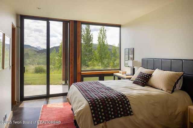 1955 W Bohnetts Rd, Jackson, WY 83001 - bedroom featuring access to exterior, finished concrete flooring, expansive windows, and a mountain view