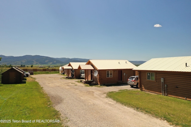 4760 W 500 W, Victor, ID 83455 - view of front of property with a mountain view, a metal roof, a storage unit, log exterior, and a front yard