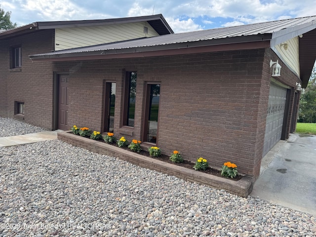 13280 N 3750 W, Felt, ID 83424 - view of side of home featuring a garage, brick siding, concrete driveway, and a metal roof