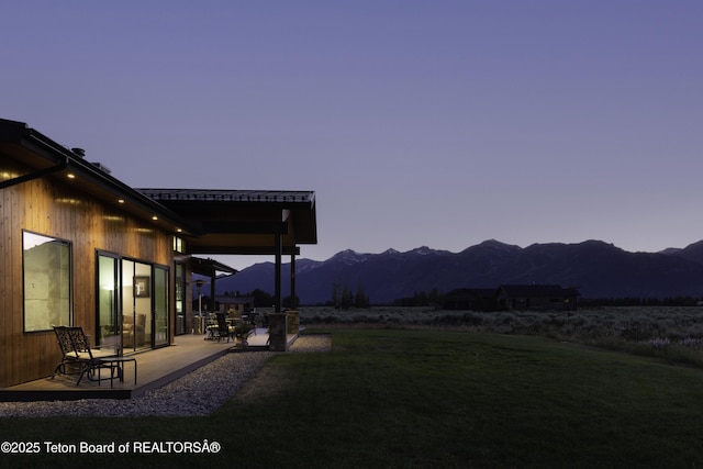580 Moulton Loop Rd, Jackson, WY 83001 - yard at dusk with a mountain view, a patio area, and a lawn