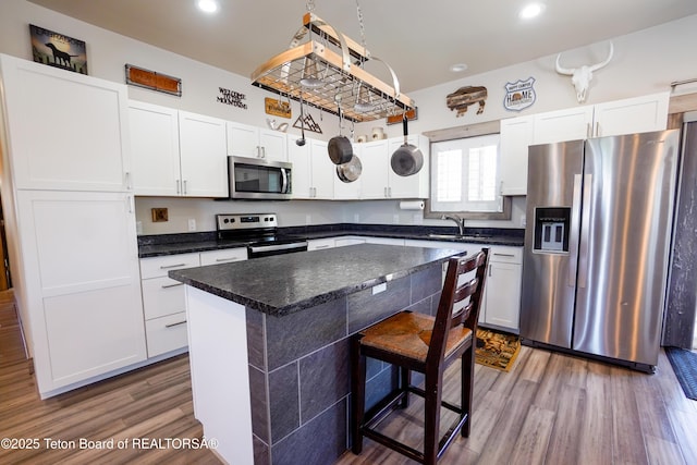 643 Country Club Way, Thayne, WY 83127 - kitchen with appliances with stainless steel finishes, wood finished floors, recessed lighting, white cabinets, and a kitchen island