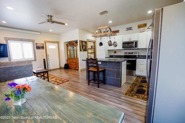 643 Country Club Way, Thayne, WY 83127 - kitchen with stainless steel appliances, a kitchen breakfast bar, wood finished floors, white cabinetry, and ceiling fan