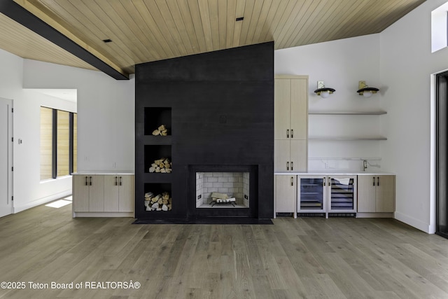 175 Huckleberry Dr, Jackson, WY 83001 - unfurnished living room with lofted ceiling, light wood-type flooring, wine cooler, wood ceiling, and a large fireplace