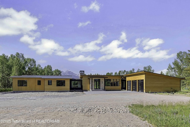 175 Huckleberry Dr, Jackson, WY 83001 - view of front of home featuring gravel driveway, a chimney, an attached garage, and a metal roof