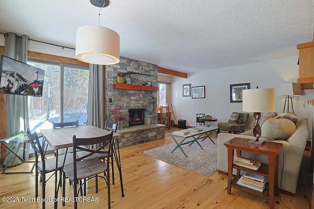 4435 Berry Dr Unit 3611, Wilson, WY 83014 - living area with a textured ceiling, a stone fireplace, light wood-style flooring, and beam ceiling