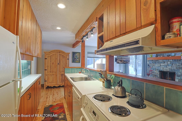 4435 Berry Dr Unit 3611, Wilson, WY 83014 - kitchen with freestanding refrigerator, stove, exhaust hood, brown cabinetry, and a textured ceiling