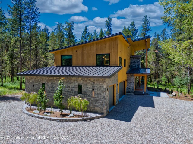 4327 Bridger Rdg, Ashton, ID 83420 - view of property exterior with a standing seam roof, an attached garage, stone siding, and driveway