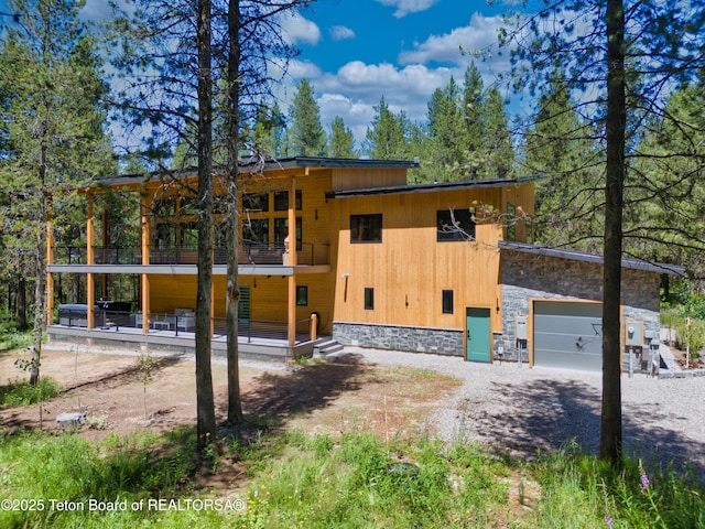 4327 Bridger Rdg, Ashton, ID 83420 - view of front of home with a balcony, gravel driveway, an attached garage, and stone siding