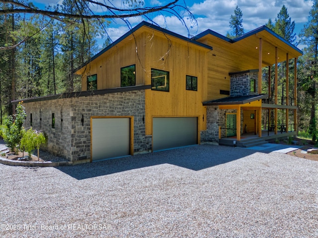4327 Bridger Rdg, Ashton, ID 83420 - modern home featuring stone siding, a garage, gravel driveway, and covered porch