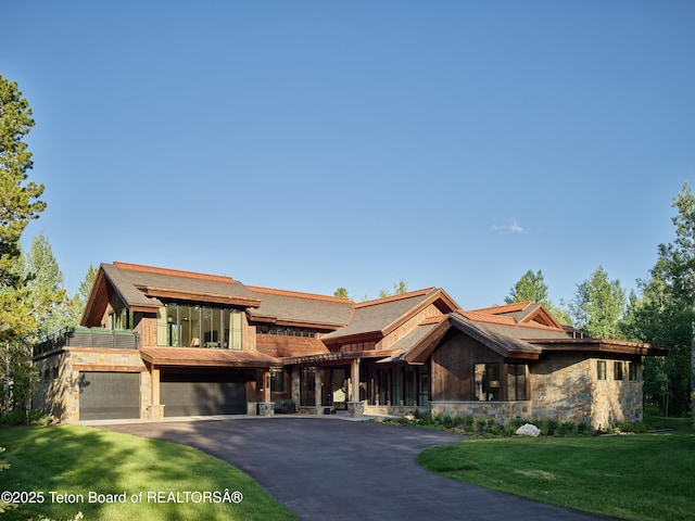 3220 N Teton Pines Dr, Wilson, WY 83014 - view of front of property with stone siding, an attached garage, asphalt driveway, and a front lawn