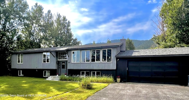 680 E Hall St, Jackson, WY 83001 - raised ranch featuring an attached garage, a front lawn, a chimney, driveway, and a shingled roof