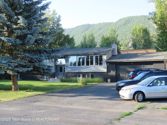 680 E Hall St, Jackson, WY 83001 - raised ranch with a garage, a mountain view, a shingled roof, a front lawn, and asphalt driveway