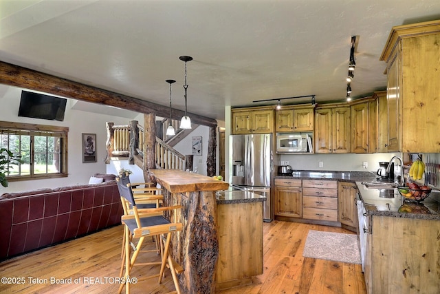 2160 Tomahawk Trl, Victor, ID 83455 - kitchen featuring stainless steel appliances, open floor plan, light wood-style flooring, a kitchen bar, and decorative light fixtures