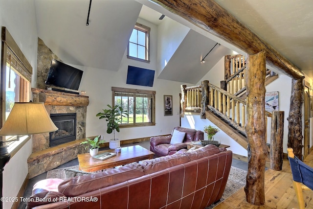 2160 Tomahawk Trl, Victor, ID 83455 - living area featuring wood-type flooring, a glass covered fireplace, stairs, high vaulted ceiling, and beam ceiling