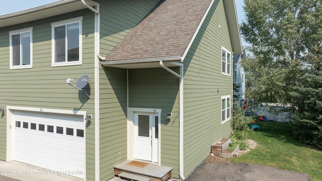 80 Eva Ln Unit 14, Victor, ID 83455 - rear view of property featuring an attached garage, a shingled roof, and a lawn