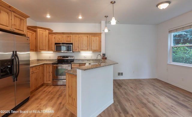 80 Eva Ln Unit 14, Victor, ID 83455 - kitchen with stainless steel appliances, a peninsula, light wood-type flooring, stone countertops, and decorative light fixtures
