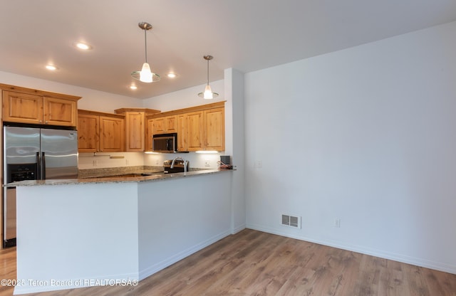 80 Eva Ln Unit 14, Victor, ID 83455 - kitchen featuring stainless steel appliances, light wood-style floors, light stone countertops, a peninsula, and hanging light fixtures