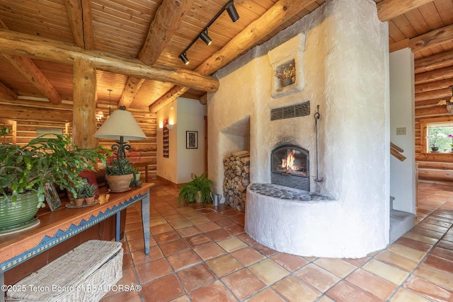 3760 N Moose-Wilson Rd, Wilson, WY 83014 - living area featuring a wooden ceiling with exposed beams, log walls, rail lighting, a warm lit fireplace, and stairs