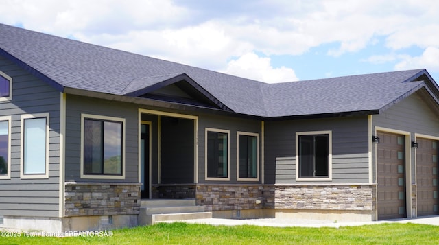 1350 Arroyo, Pinedale, WY 82941 - view of front facade with stone siding, a garage, and roof with shingles