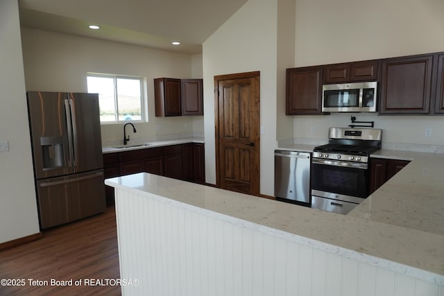 1350 Arroyo, Pinedale, WY 82941 - kitchen featuring appliances with stainless steel finishes, dark brown cabinets, dark wood-style floors, light stone countertops, and vaulted ceiling
