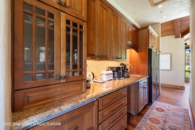 500 E Buckwheat Cir, Jackson, WY 83001 - kitchen featuring dark wood-style flooring, glass insert cabinets, brown cabinets, light stone countertops, and beamed ceiling