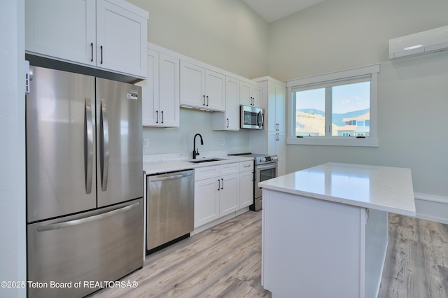 151 Stonefly Ln, Swan Valley, ID 83449 - kitchen with stainless steel appliances, light wood-style floors, white cabinets, and a wall mounted air conditioner