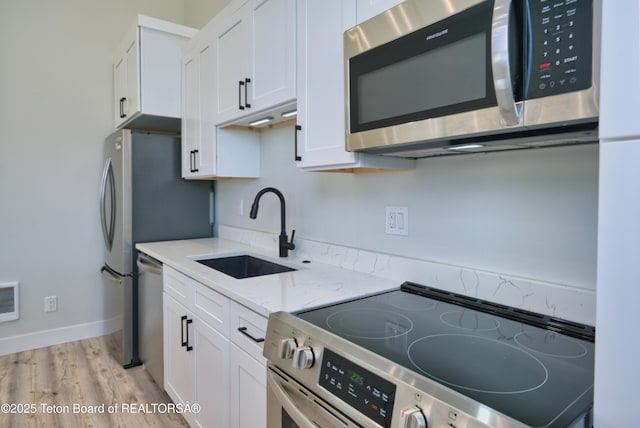 151 Stonefly Ln, Swan Valley, ID 83449 - kitchen with stainless steel appliances, white cabinets, light wood-style flooring, and light stone countertops