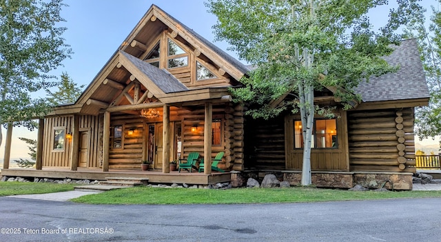 8157 Ripplinger Rd, Driggs, ID 83422 - cabin featuring log siding, covered porch, and a shingled roof