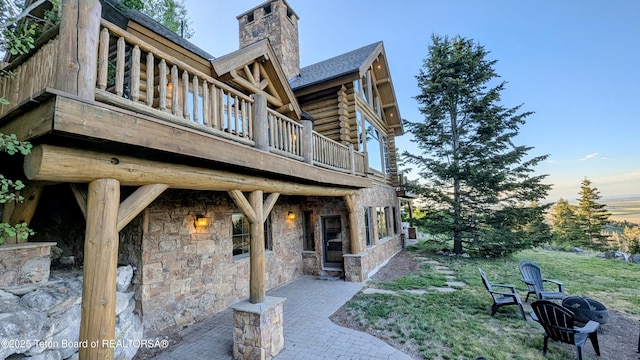 8157 Ripplinger Rd, Driggs, ID 83422 - back of house with log siding, a chimney, a yard, and stone siding