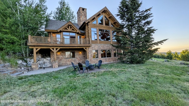 8157 Ripplinger Rd, Driggs, ID 83422 - rear view of house with log exterior, a yard, a chimney, stone siding, and a deck