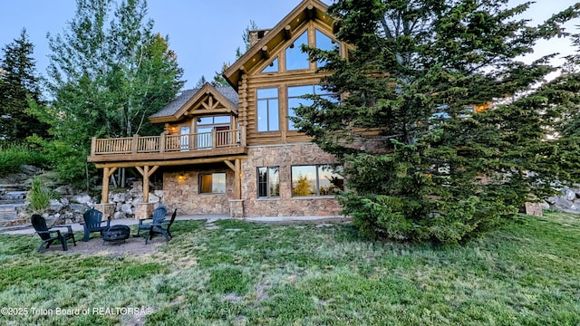 8157 Ripplinger Rd, Driggs, ID 83422 - back of house with stone siding, an outdoor fire pit, a yard, log siding, and a wooden deck