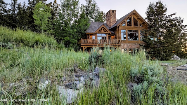 8157 Ripplinger Rd, Driggs, ID 83422 - back of property featuring log exterior, a chimney, and a wooden deck