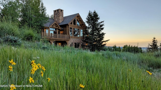 8157 Ripplinger Rd, Driggs, ID 83422 - back of property at dusk with log exterior, a chimney, and a shingled roof