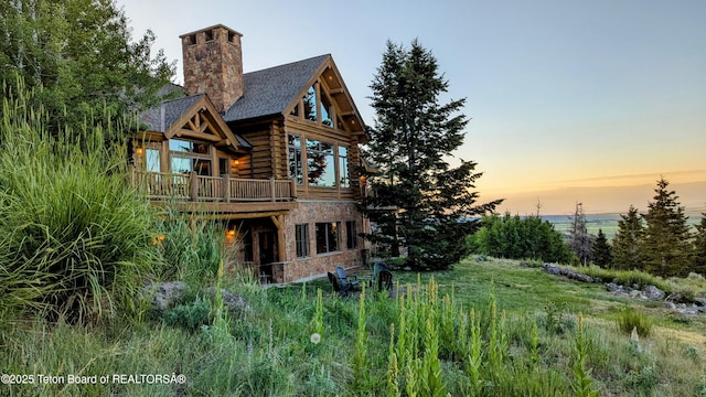 8157 Ripplinger Rd, Driggs, ID 83422 - rear view of house featuring log exterior, a chimney, stone siding, a deck, and roof with shingles
