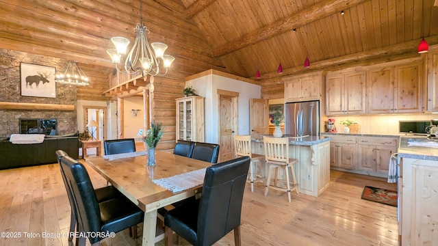 8157 Ripplinger Rd, Driggs, ID 83422 - dining space featuring light wood finished floors, a wooden ceiling with exposed beams, a chandelier, high vaulted ceiling, and a fireplace