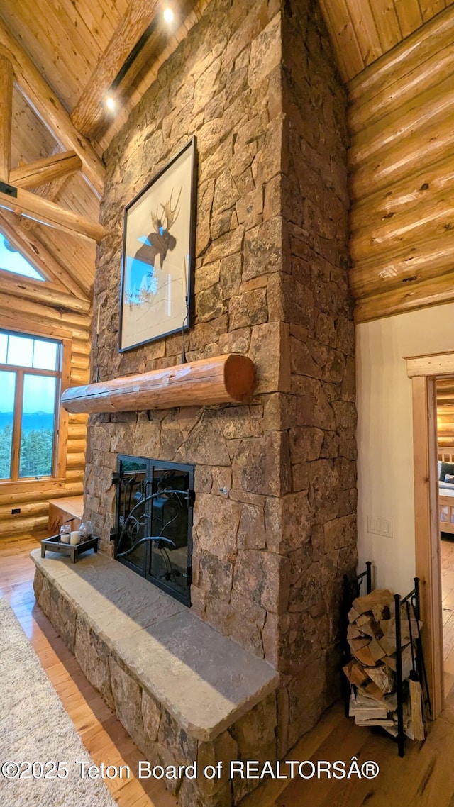 8157 Ripplinger Rd, Driggs, ID 83422 - living room with rustic walls, a wood ceiling with exposed beams, hardwood / wood-style floors, a stone fireplace, and high vaulted ceiling