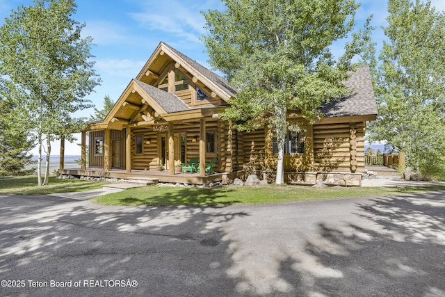 8157 Ripplinger Rd, Driggs, ID 83422 - cabin with log exterior, a porch, and a shingled roof