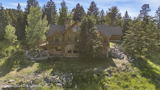 8157 Ripplinger Rd, Driggs, ID 83422 - back of property featuring stone siding, a chimney, a deck, log siding, and roof with shingles