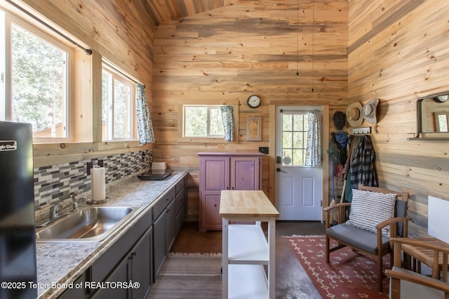 66 Elkhorn Dr, Thayne, WY 83127 - kitchen with butcher block counters, freestanding refrigerator, wooden walls, vaulted ceiling, and decorative backsplash