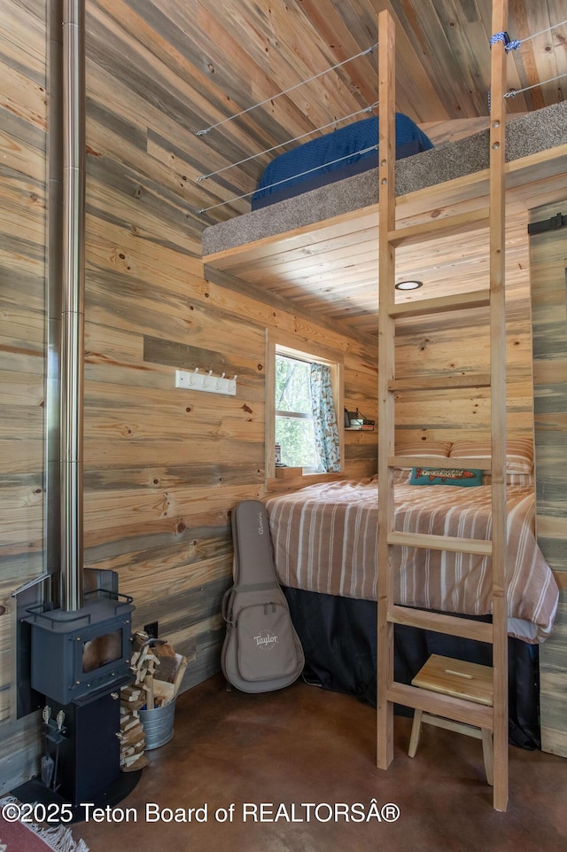 66 Elkhorn Dr, Thayne, WY 83127 - bedroom featuring finished concrete floors, wood walls, a wood stove, and wooden ceiling