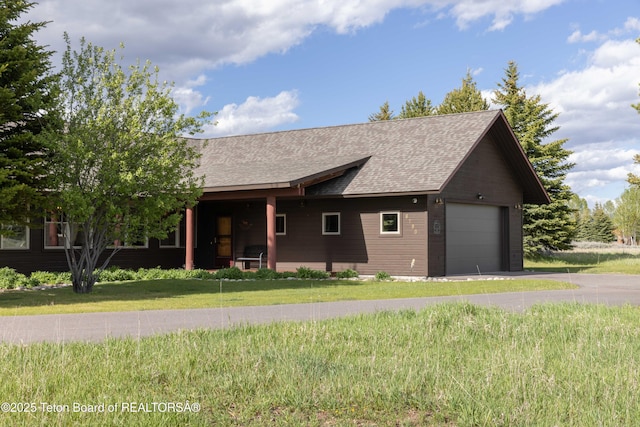 6790 N Timothy Rd, Jackson, WY 83001 - view of front facade featuring a front lawn, a shingled roof, and a garage