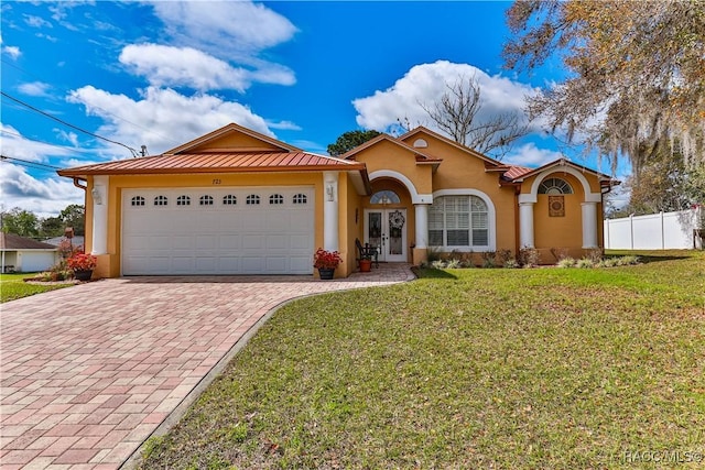 view of front of house featuring fence, french doors, decorative driveway, stucco siding, and a front lawn