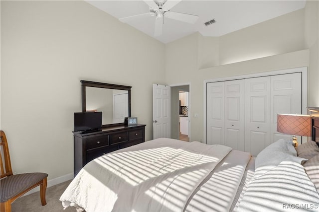 bedroom with ceiling fan, a towering ceiling, carpet floors, and a closet