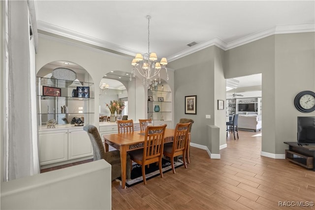 dining area featuring an inviting chandelier, ornamental molding, light hardwood / wood-style floors, and built in features