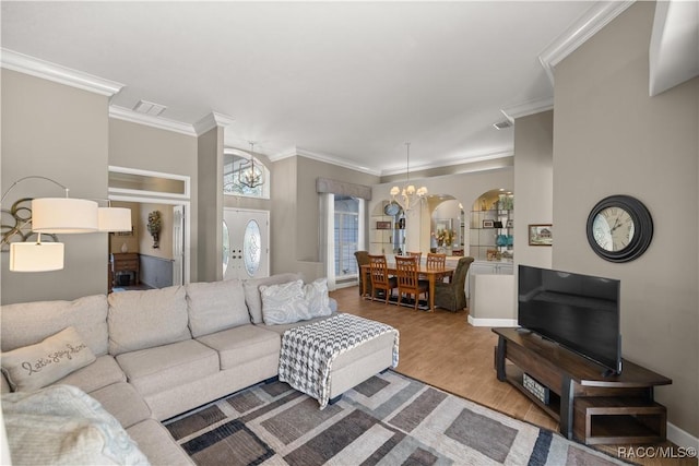 living room featuring a notable chandelier, hardwood / wood-style flooring, and ornamental molding