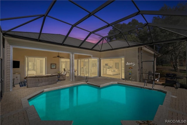 pool at dusk with outdoor lounge area, ceiling fan, a lanai, and a patio